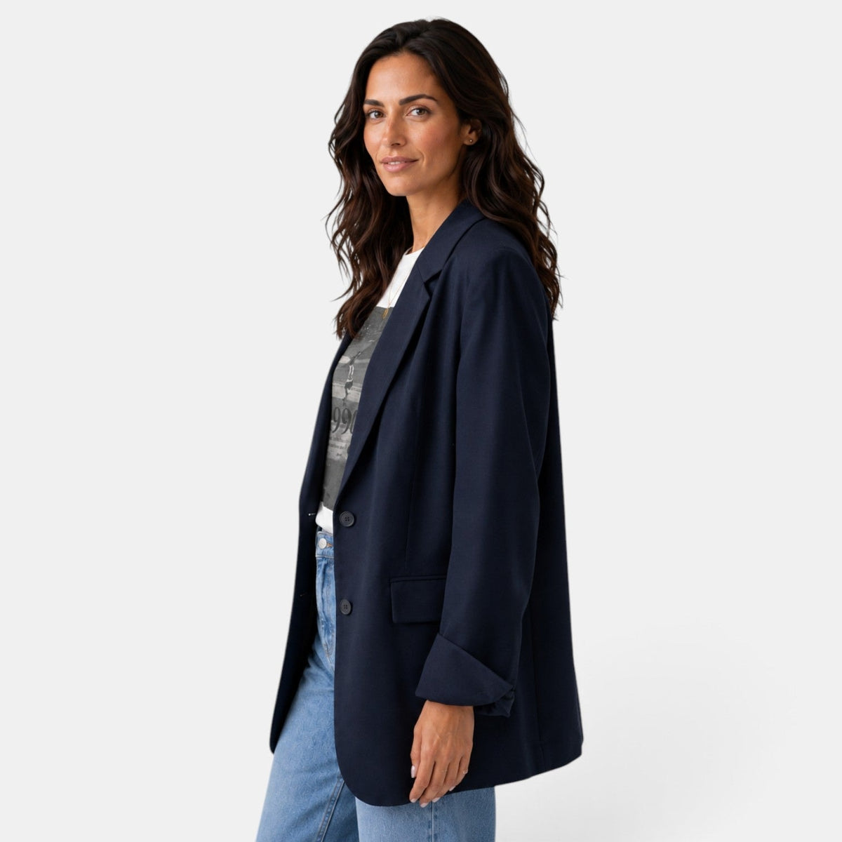 Side view of the navy blazer highlighting its elongated relaxed silhouette, two-button front, notched lapel, and side flap pocket.