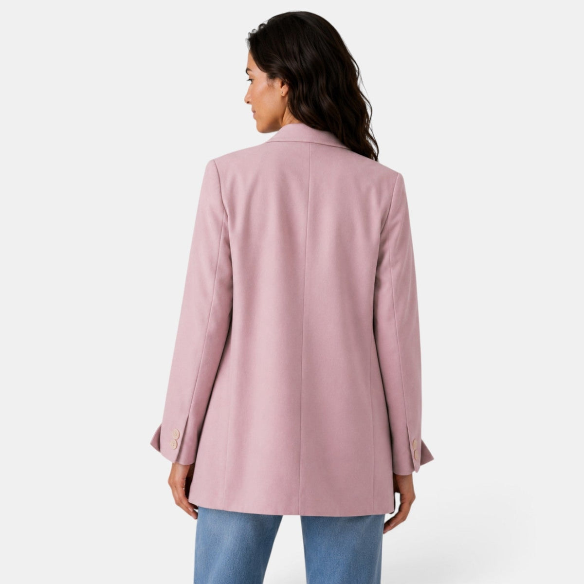 Back view of the blush pink oversized blazer showing its long relaxed cut, center back seam, and buttoned split cuffs.