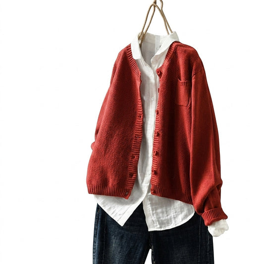 Red oversized button cardigan layered open over a white collared shirt, with long sleeves, ribbed edges, and a patch chest pocket.