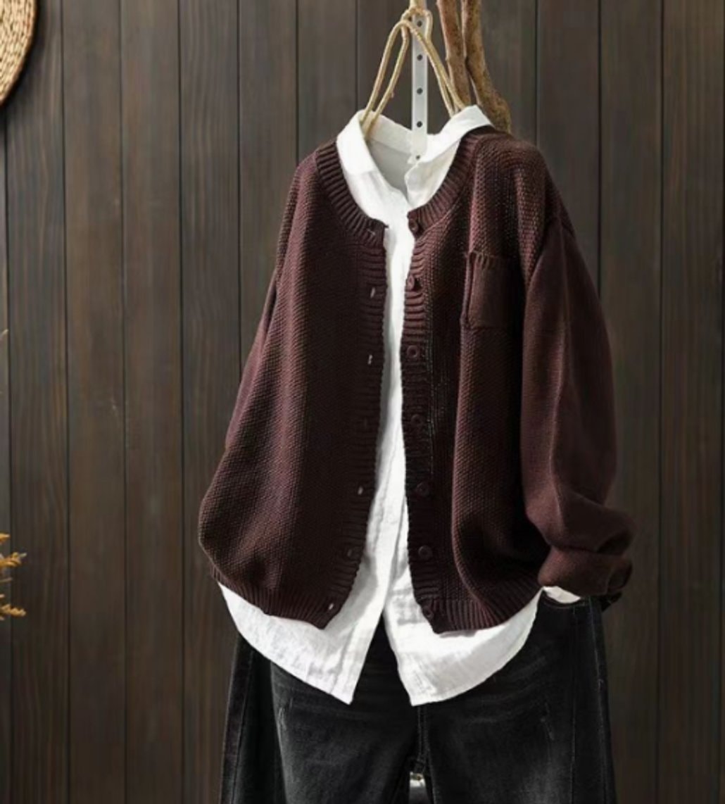 Deep burgundy oversized cardigan styled over a white shirt, shown with its full button front and long sleeves against a dark wood backdrop.