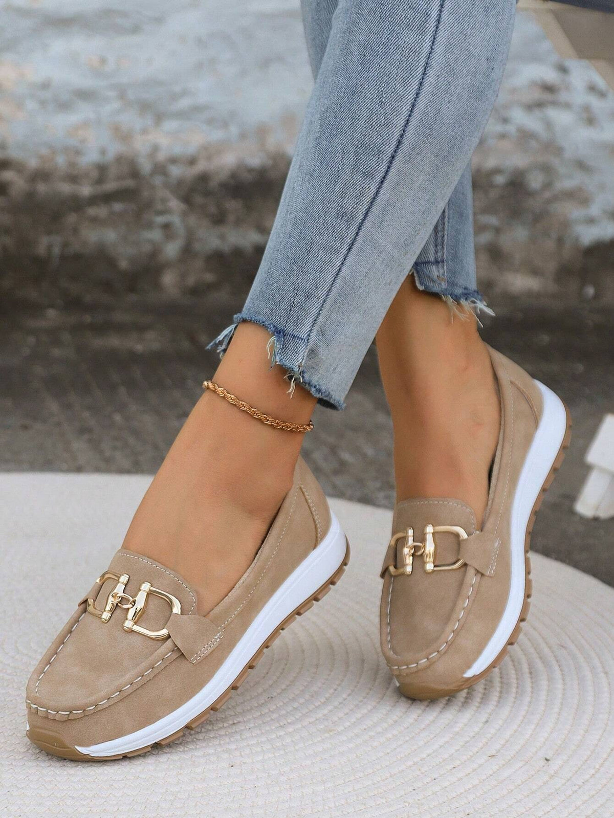Beige buckle-detail platform loafers worn with cropped jeans, shown from an angled front view.