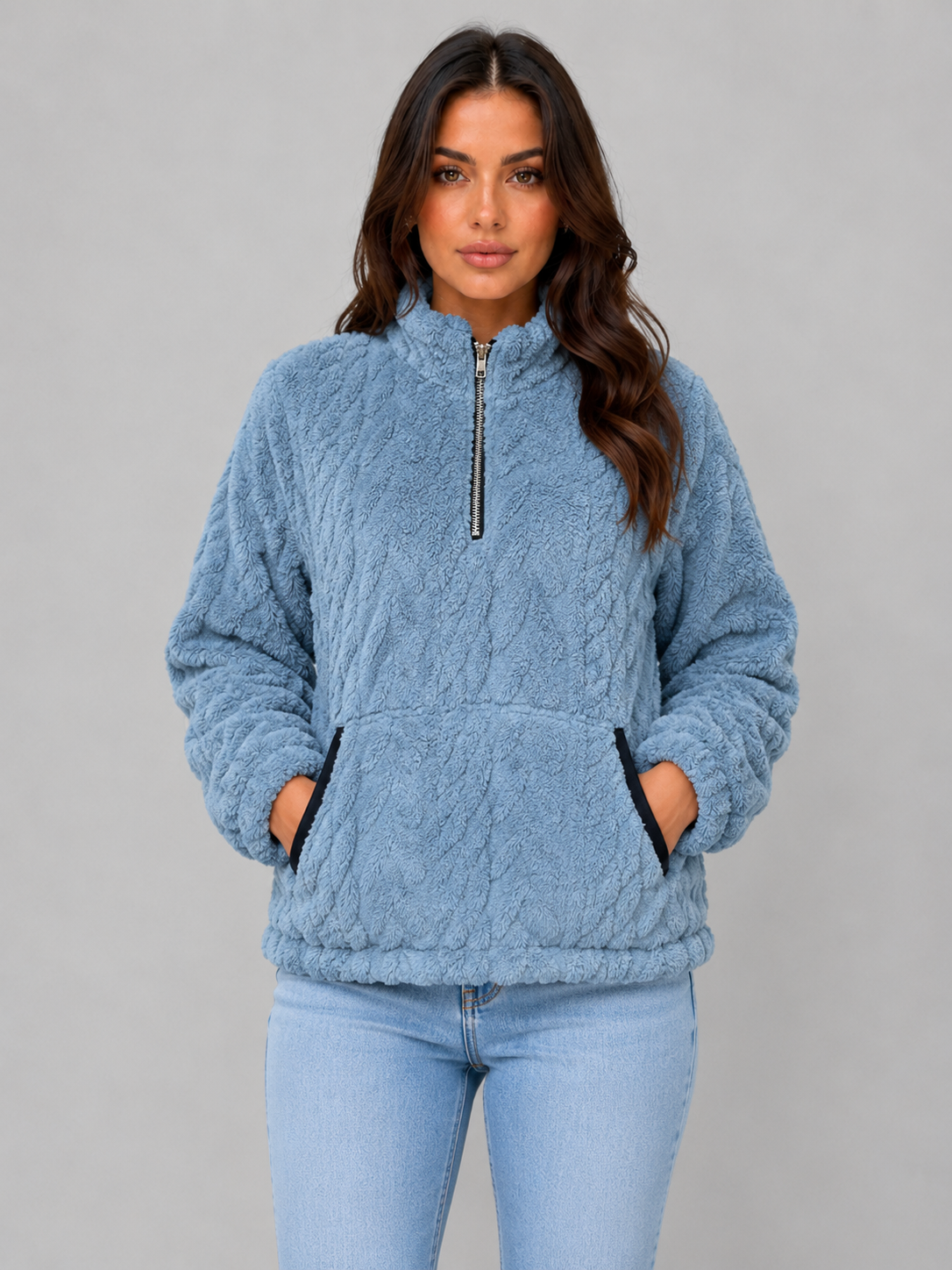 Blue plush half-zip pullover with both hands placed in the front pocket, shown from the front.