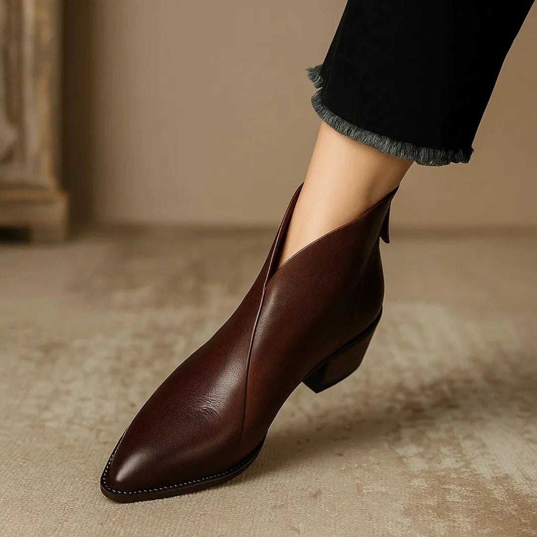 Brown pointed-toe ankle boot shown at a three-quarter angle, emphasizing the curved shaft and low heel.