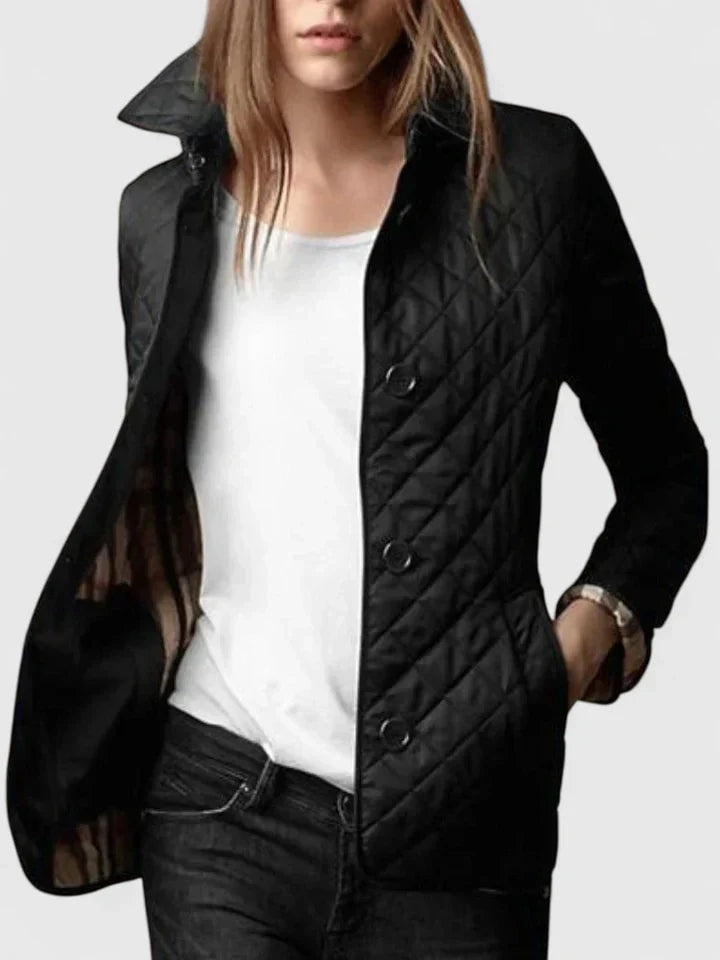 Black quilted button-front jacket with a pointed collar, long sleeves, and hip-length cut, worn open over a white top.