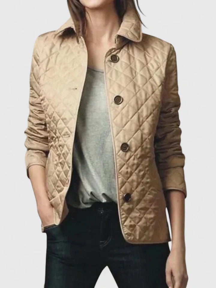 Tan quilted jacket shown closed with a pointed collar, four dark buttons, long sleeves, and side pockets.