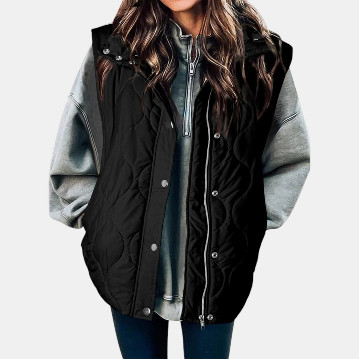 Black quilted hooded longline puffer vest layered over a grey sweatshirt, shown from the front with snap and zip closures.