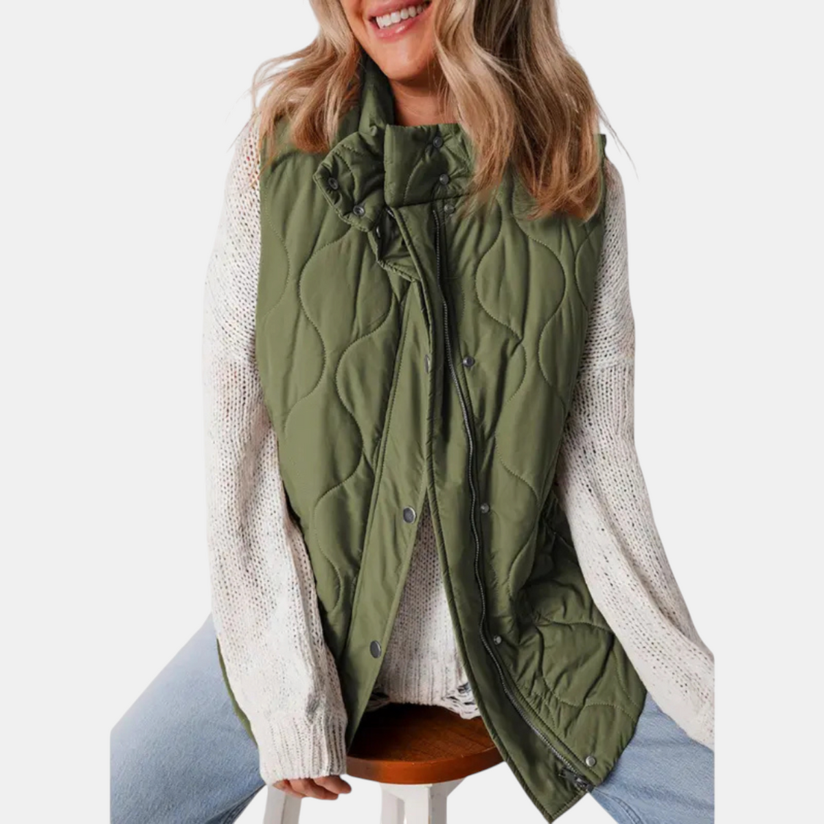 Olive quilted hooded vest worn open over a light sweater, revealing its front zip and snap closures.