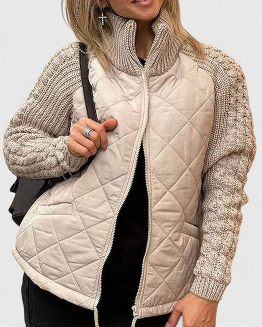 Beige quilted jacket with textured cable-knit sleeves, a high stand collar, front zip, and two side pockets shown partially open.