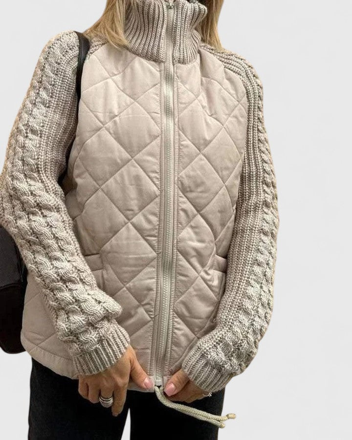 Front view of the beige quilted jacket fully zipped, highlighting its high stand collar, textured sleeves, and ribbed cuffs.