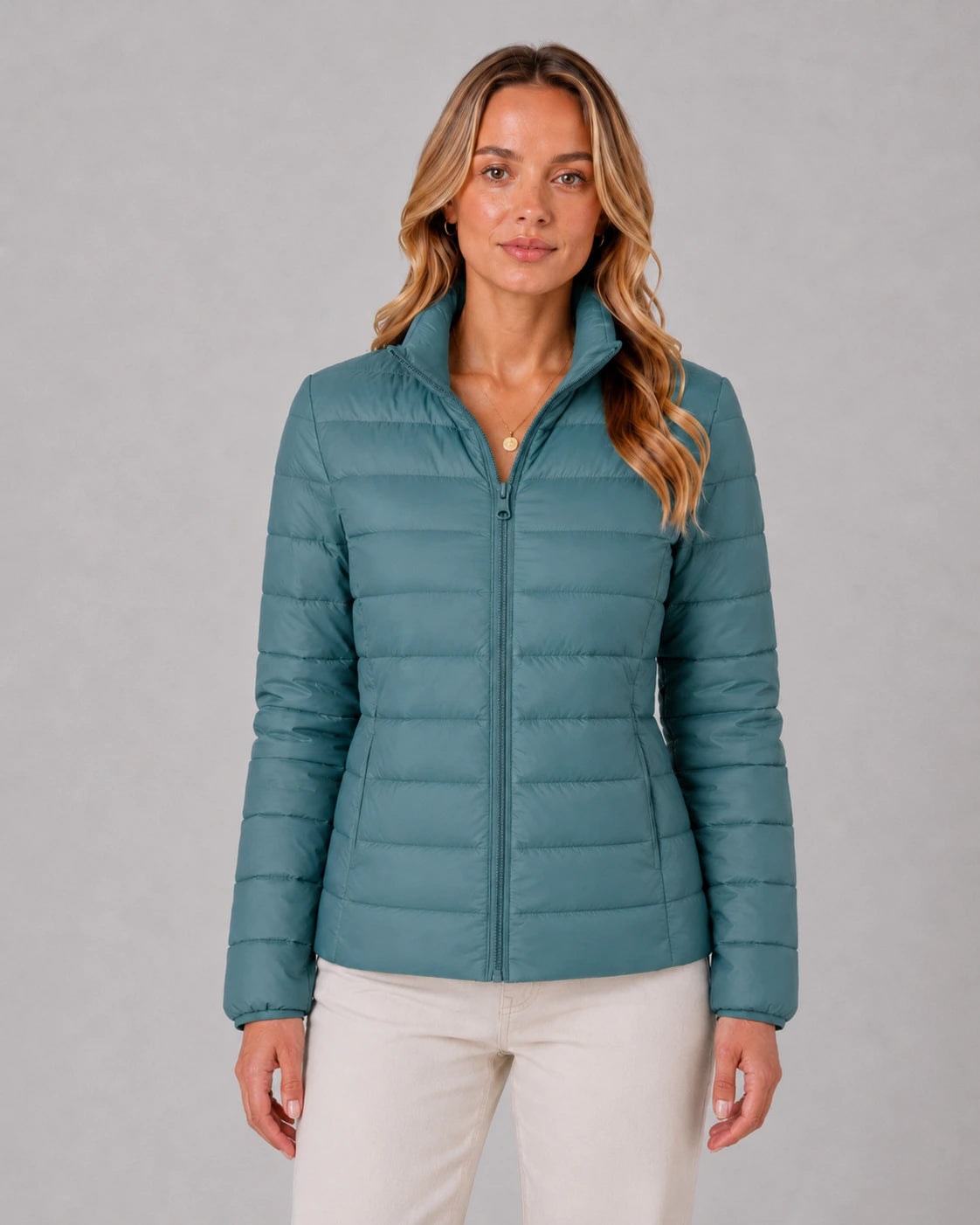 Front view of the teal quilted jacket fully zipped, highlighting its structured hip-length shape and raised stand collar.