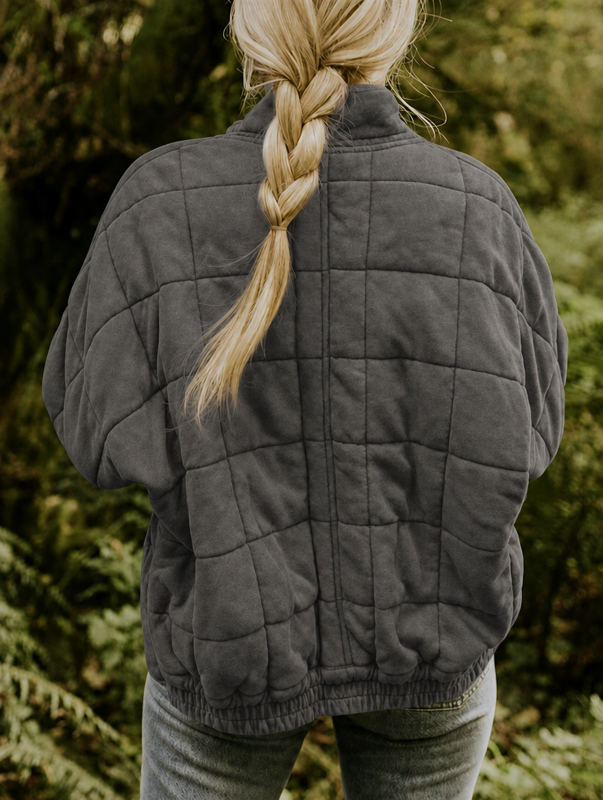 Back view of the charcoal jacket highlighting the geometric quilt pattern, relaxed shape, and gathered hem.
