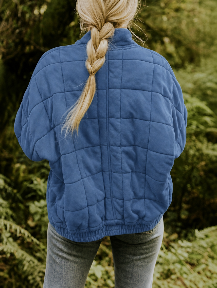 Back view of the blue jacket displaying the full geometric stitch pattern and gathered lower hem.