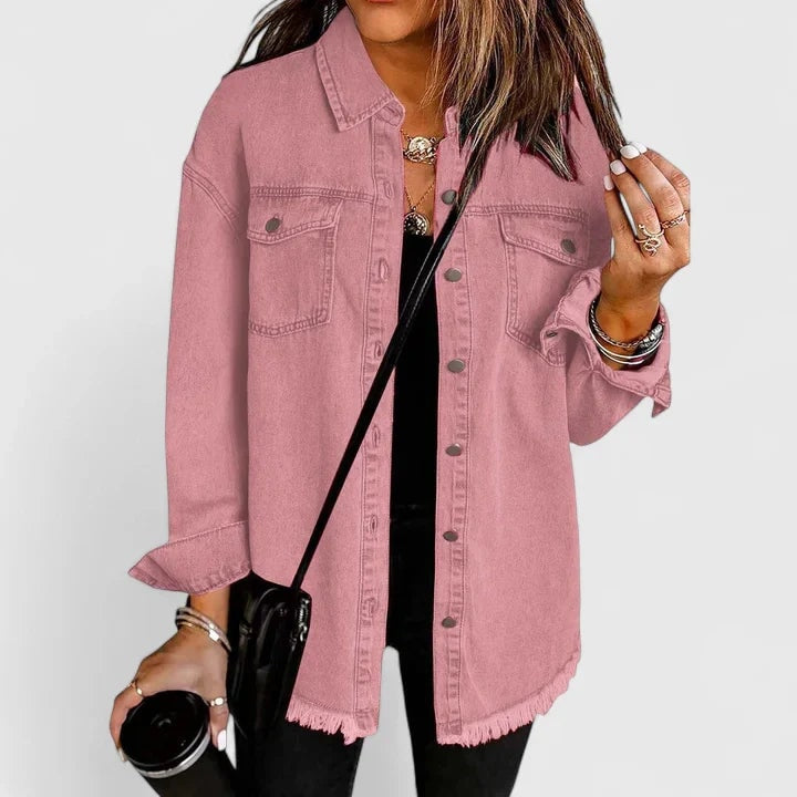 Relaxed pink button-front trucker jacket with pointed collar, two chest pockets, long sleeves, and a raw frayed hem over a black top.