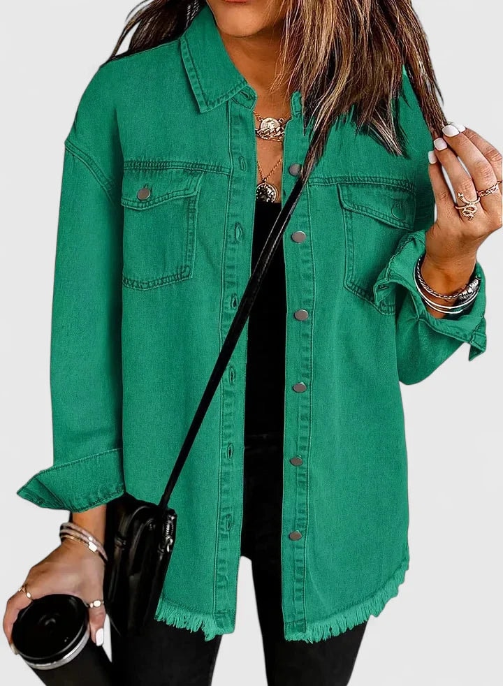 Relaxed green trucker jacket styled open over black clothing, showing button-flap chest pockets and a frayed hem.