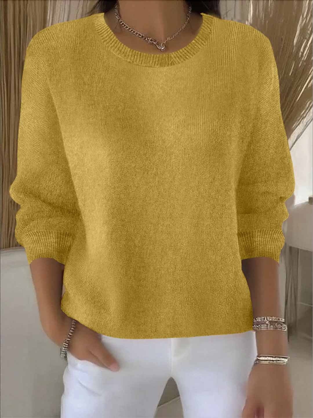 Mustard yellow relaxed crew neck sweater with long sleeves, ribbed cuffs and hem, styled with white pants.