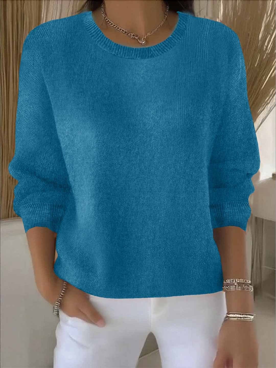 Bright blue relaxed crew neck sweater featuring long sleeves and gathered ribbed cuffs, paired with white pants.
