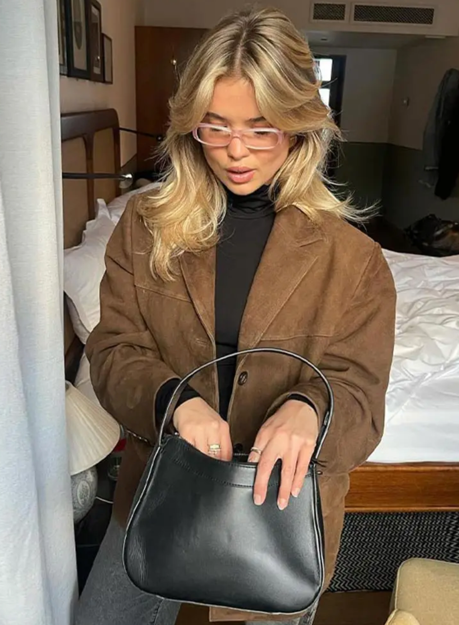 Brown relaxed blazer styled over a black high-neck top, viewed from above to emphasize the notch lapels, button closure, long sleeves, and front pocket placement.