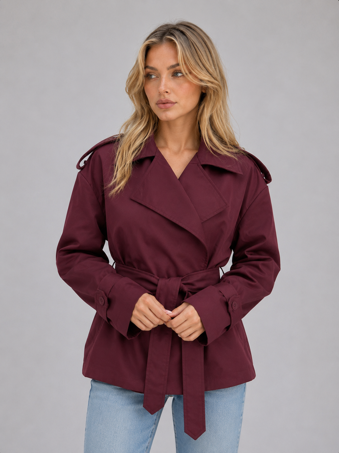 Burgundy short trench coat shown from the front with the waist belt tied, classic lapels, shoulder epaulettes, and adjustable cuffs.