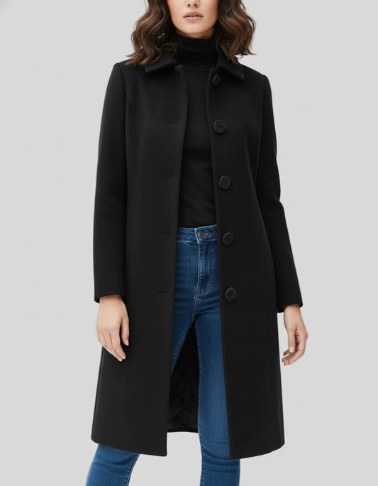 Black single-breasted knee-length coat with a stand collar, long sleeves, and gently shaped fit, worn open over a black top and jeans.