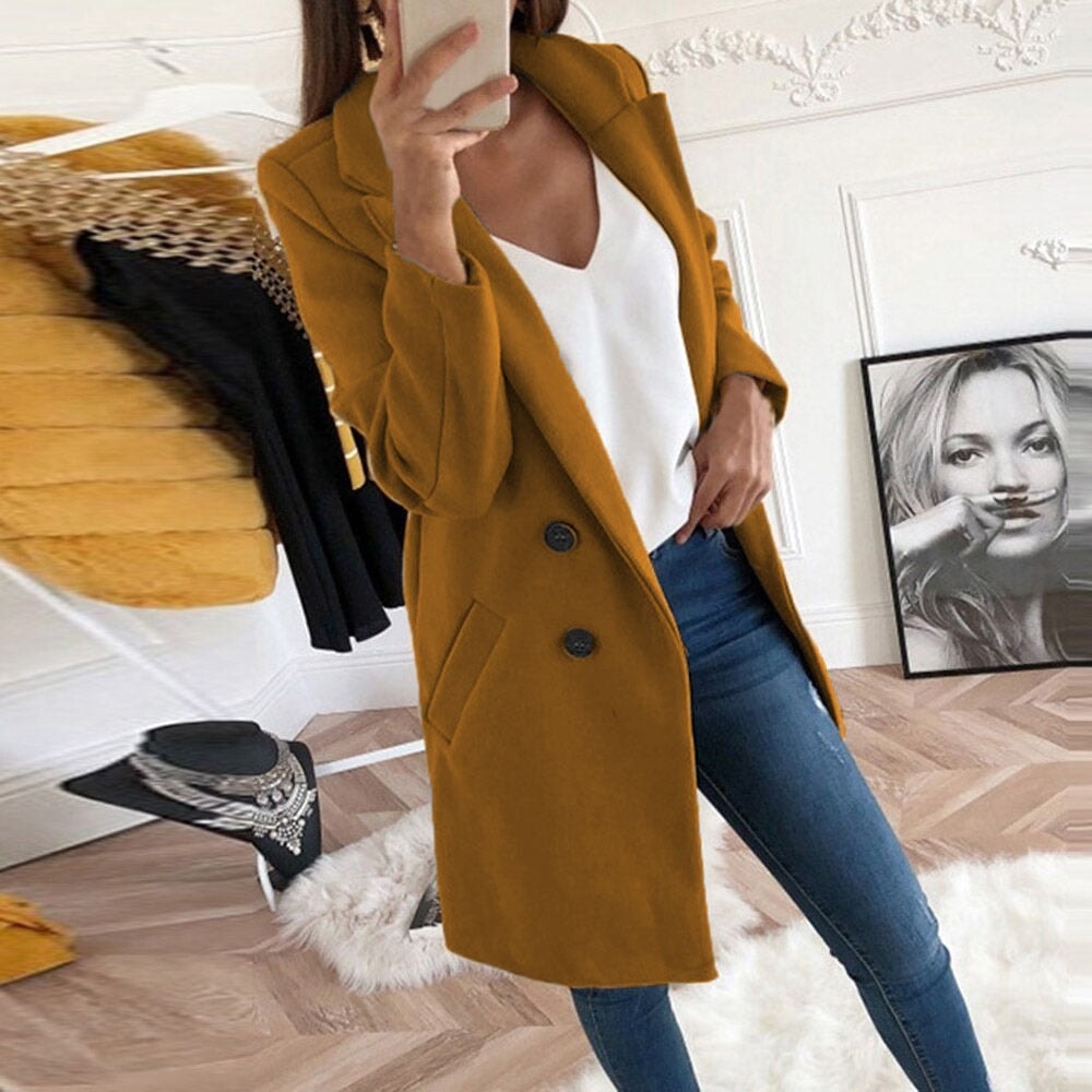 Mustard yellow mid-thigh coat displaying its classic lapels, two-button front, and angled hip pockets while worn with denim.