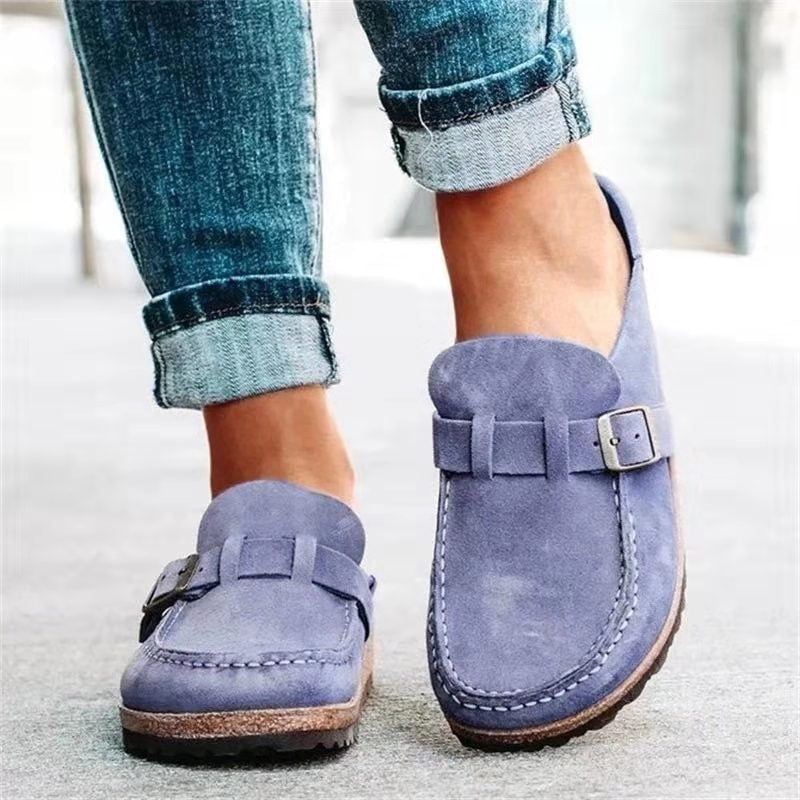 Lavender slip-on flats shown from a front angle, featuring matching buckle straps, rounded toes, stitched edges, and low-profile soles.