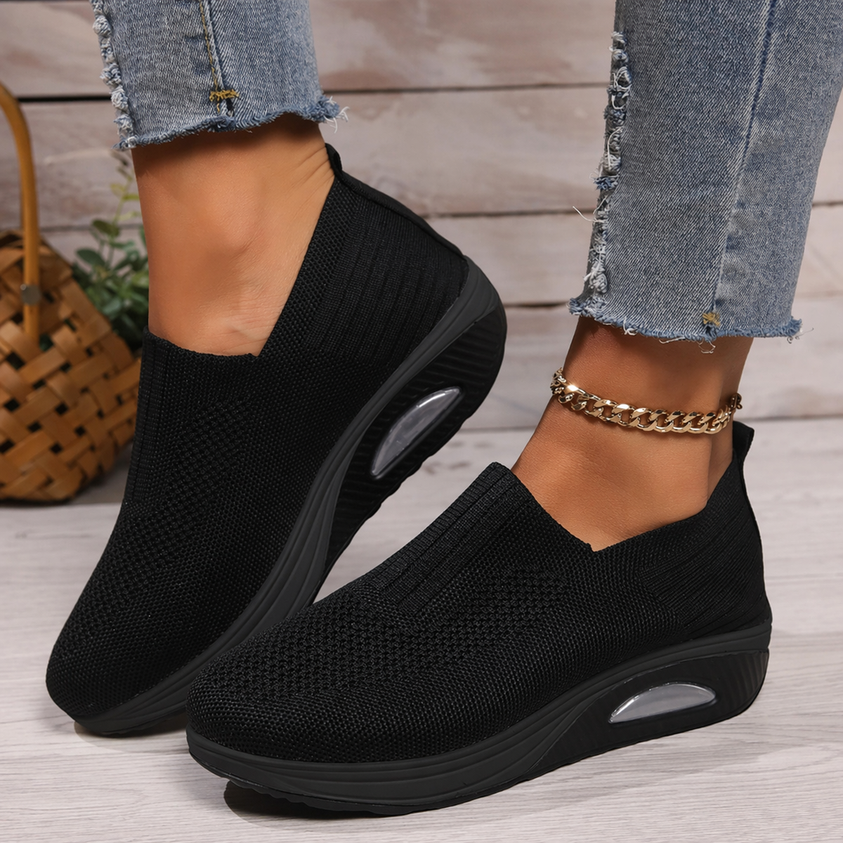 Black slip-on platform walking sneakers shown on feet from a side angle, with textured uppers and oval sole accents.