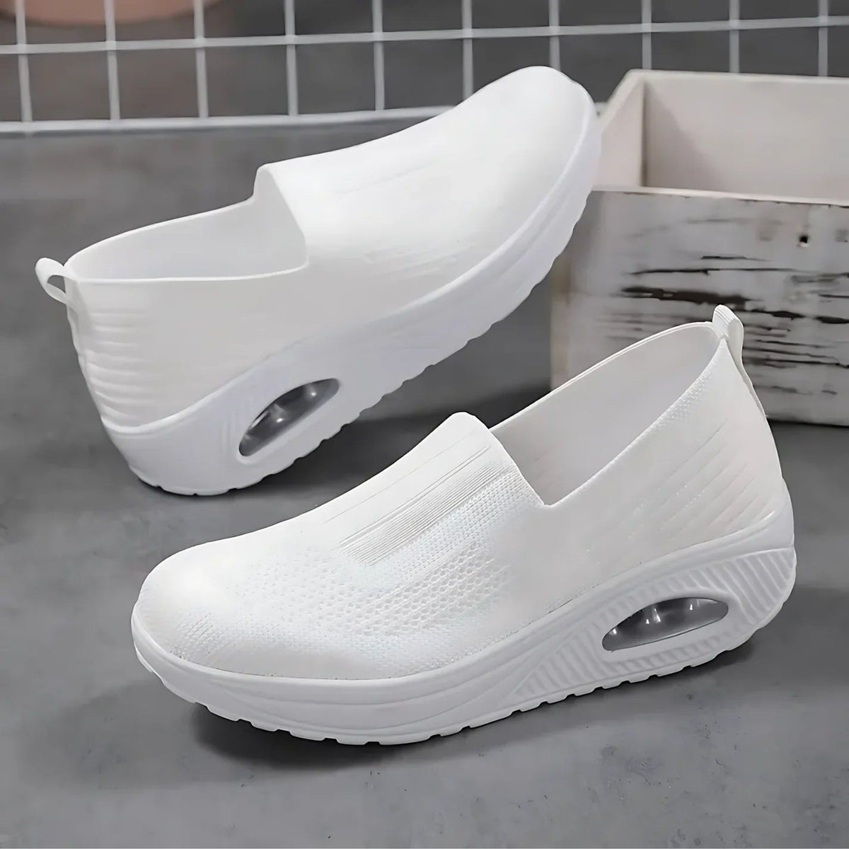 White slip-on platform sneakers displayed separately, showing their textured uppers, raised soles, and oval side accents.