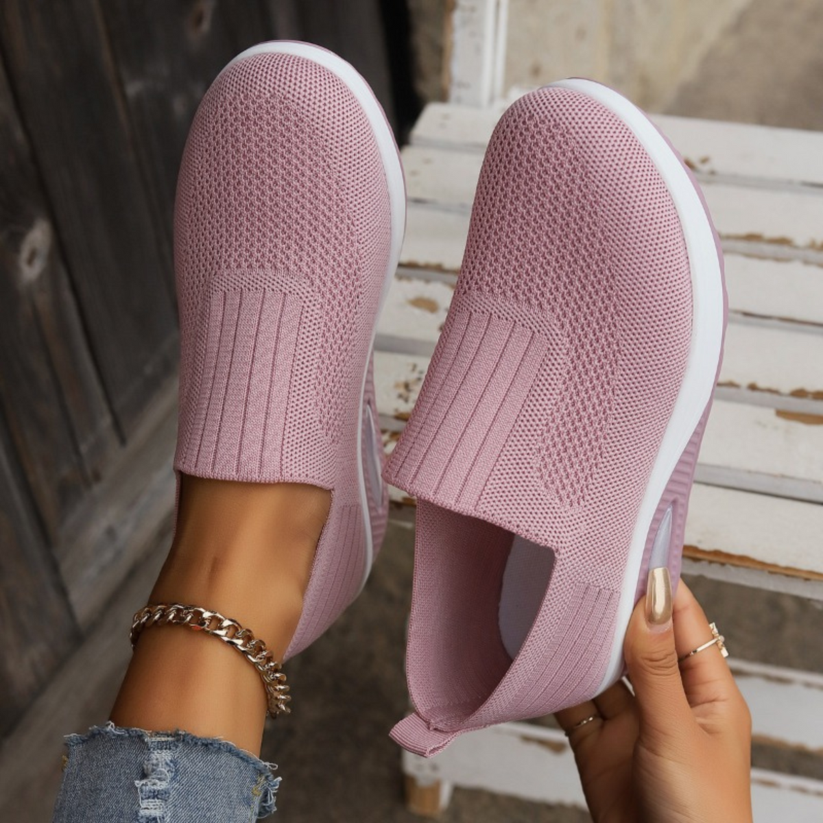 Pair of pink slip-on platform sneakers held upright to show the rounded toes, textured uppers, and open entry openings.