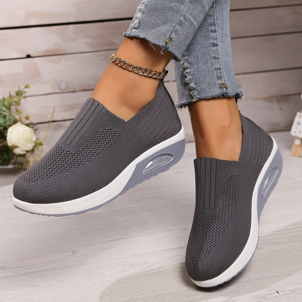 Gray slip-on platform sneakers shown in motion, emphasizing the flexible low-cut shape and raised soles with oval side details.
