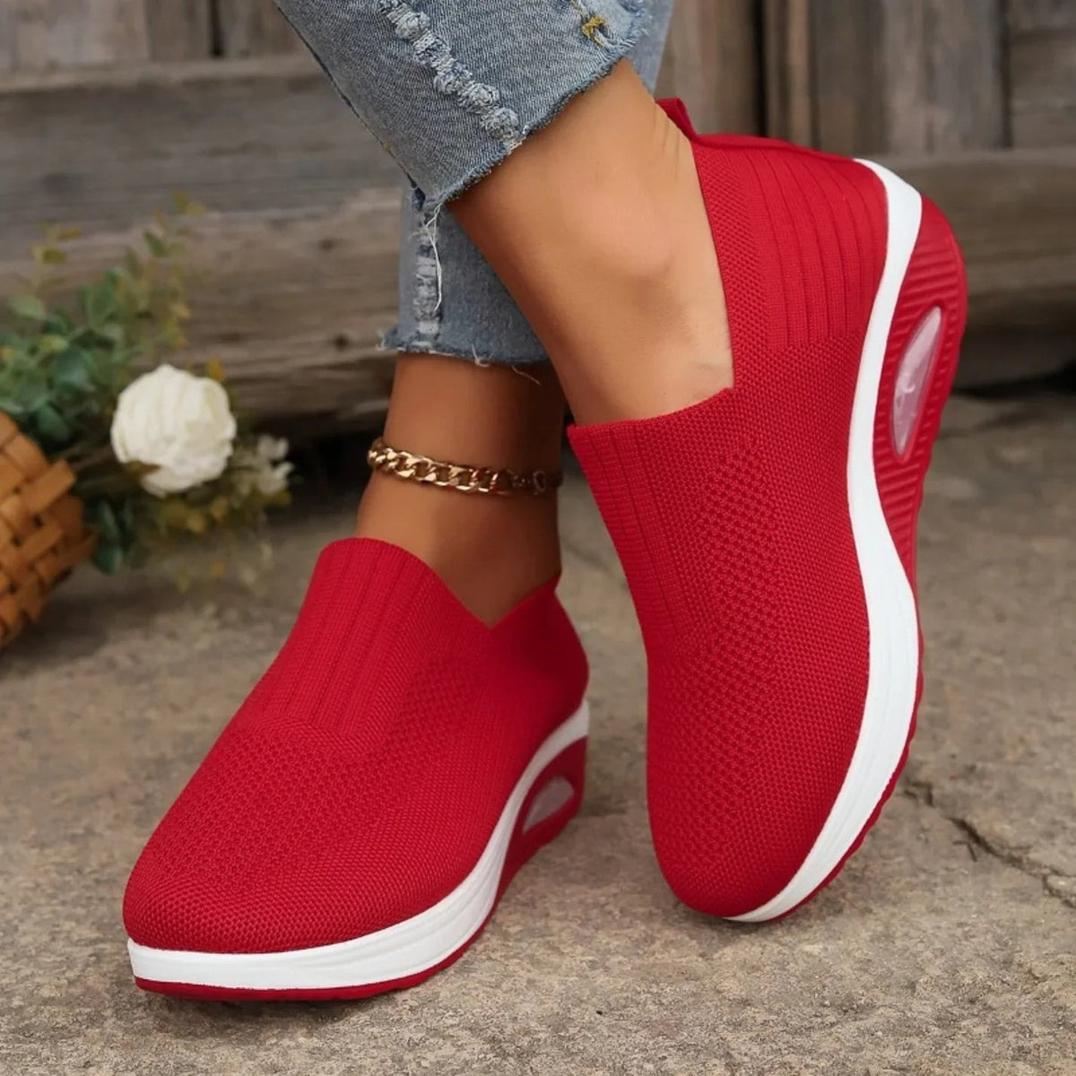 Red slip-on platform sneakers worn in a close side view, featuring textured uppers, white midsole bands, and red raised soles.