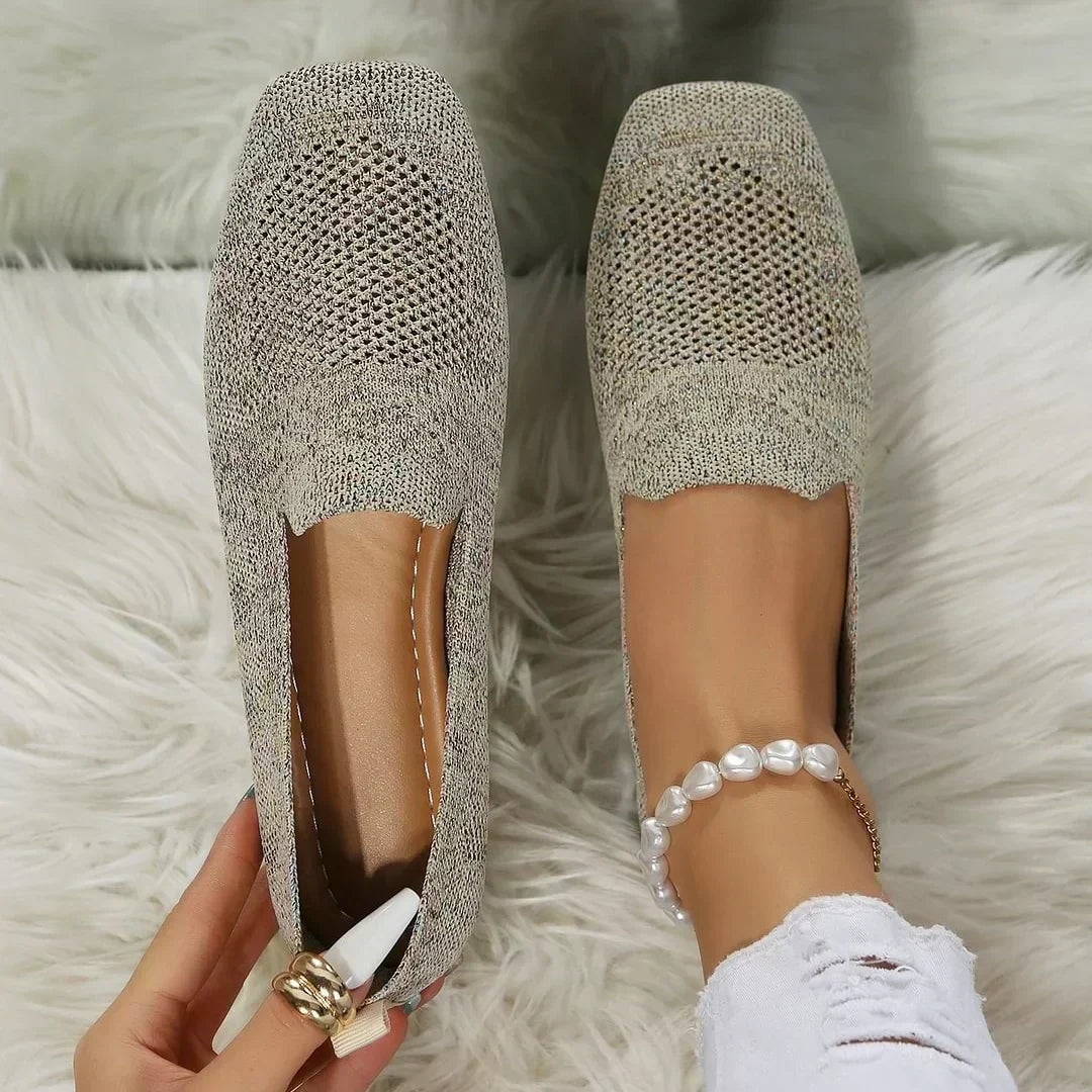 Pair of light beige square-toe slip-on flats shown from above, highlighting the open-knit uppers and flat profile.