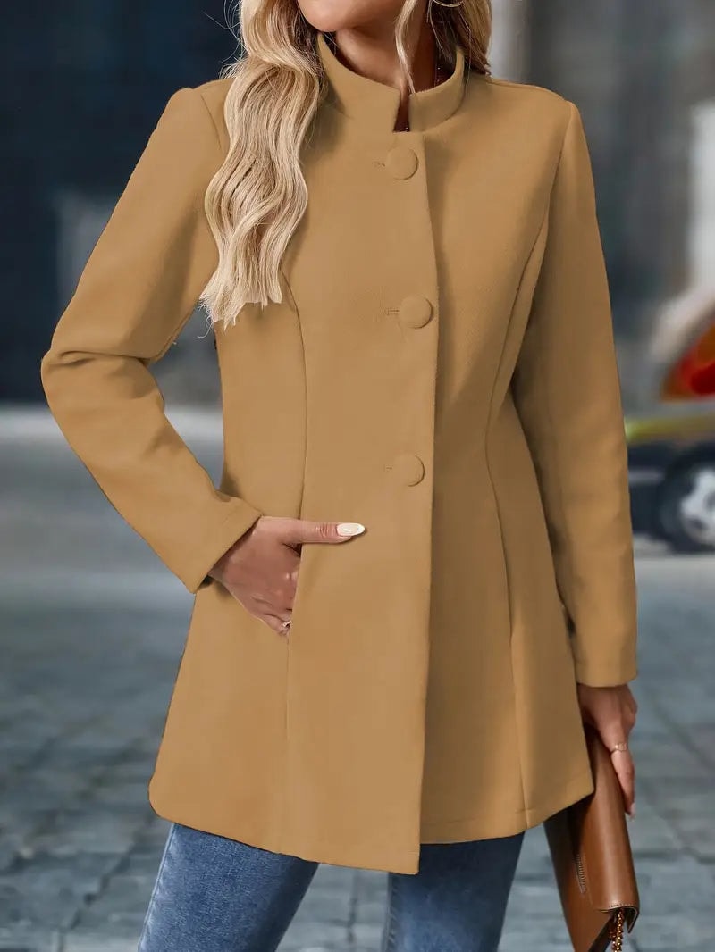 Tan stand-collar coat fully buttoned from the front, showing its clean structured closure and long sleeves.