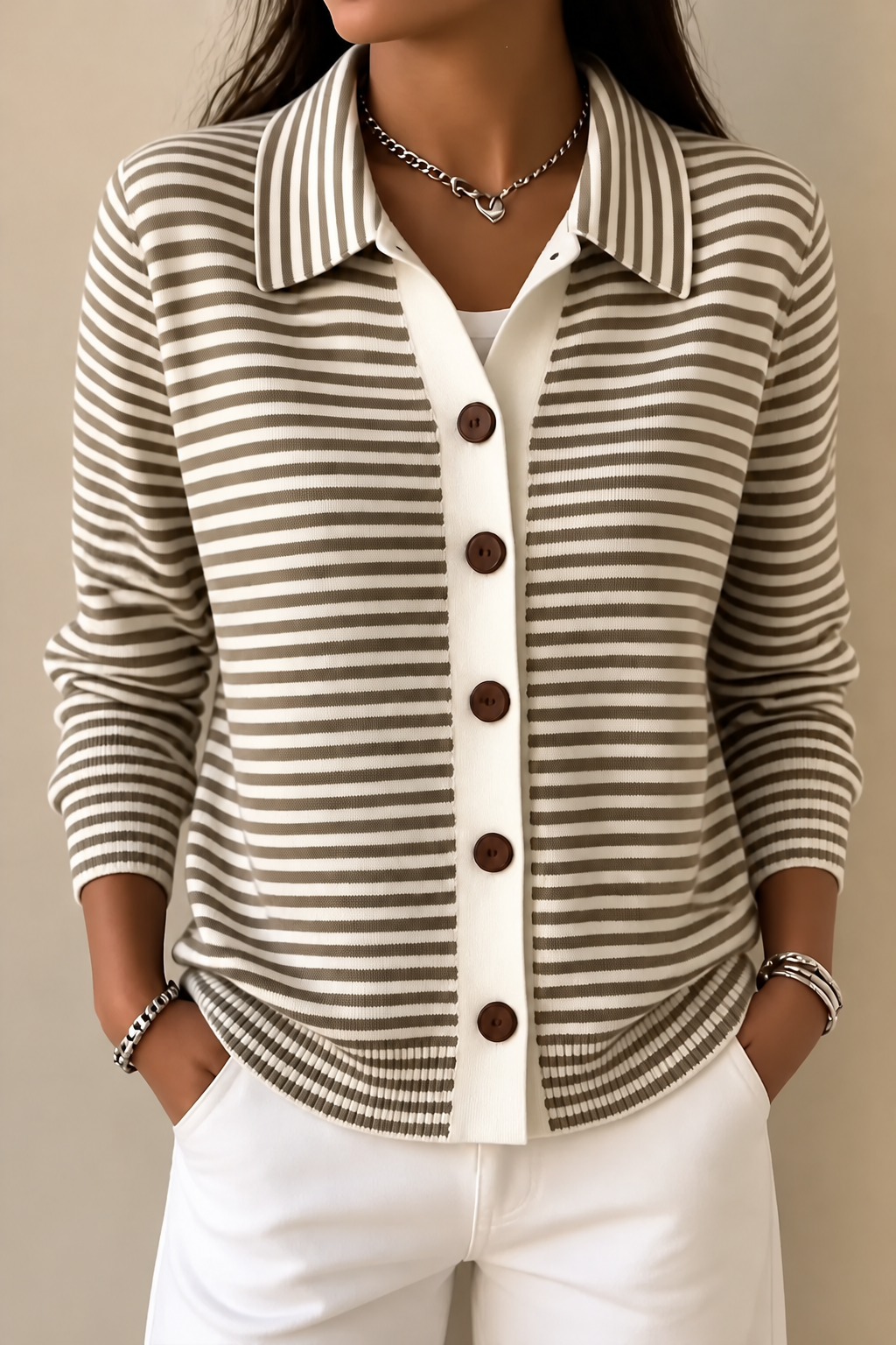 Front view of the taupe-and-cream cardigan worn open at the neckline with hands in trouser pockets.