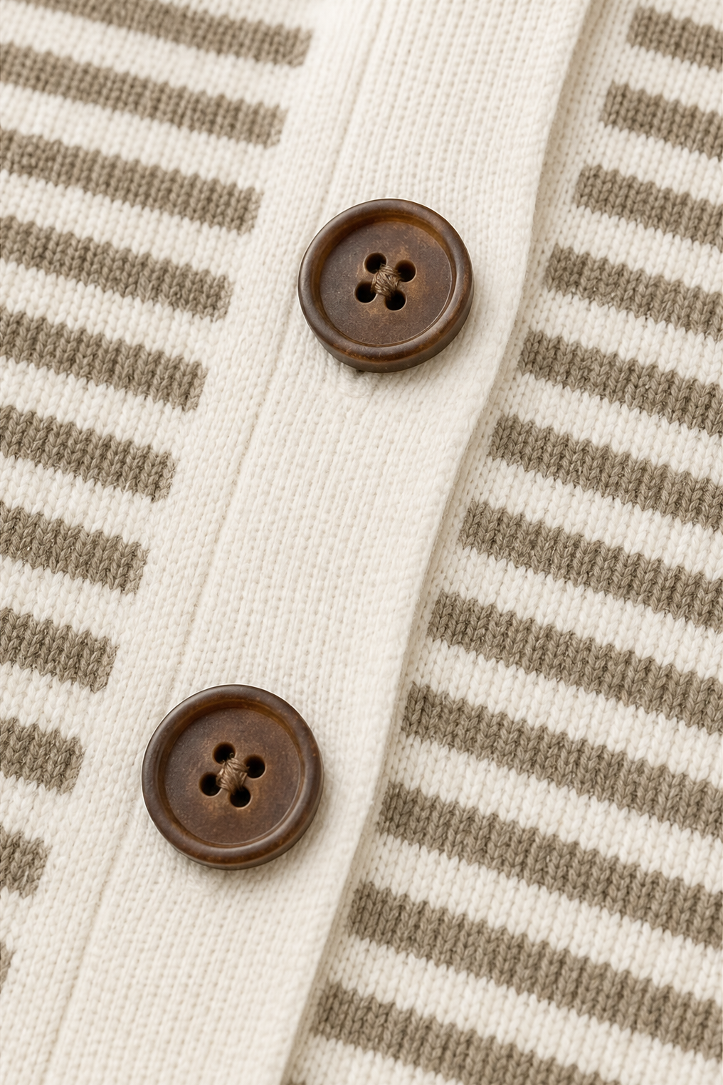 Detail of two brown front buttons set into the cream button placket between the striped panels.