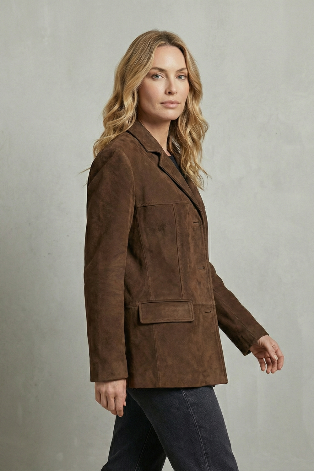 Three-quarter side view highlighting the blazer’s extended length, notched lapel, long sleeves, and front flap pocket.