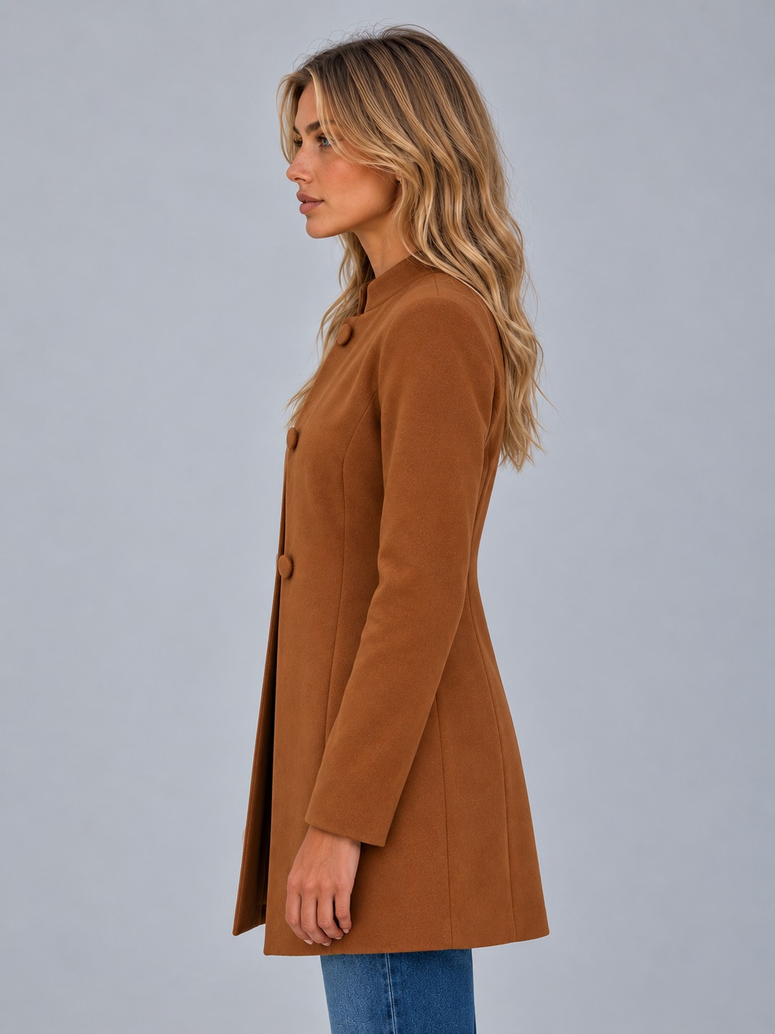 Side view of the brown tailored coat, highlighting its longline length, fitted waist and clean round neckline.