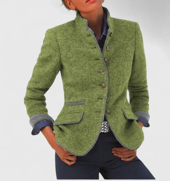 Green tailored cardigan jacket worn with the sleeves turned back to reveal contrasting cuffs and matching contrast edging around the collar, front, and pockets.