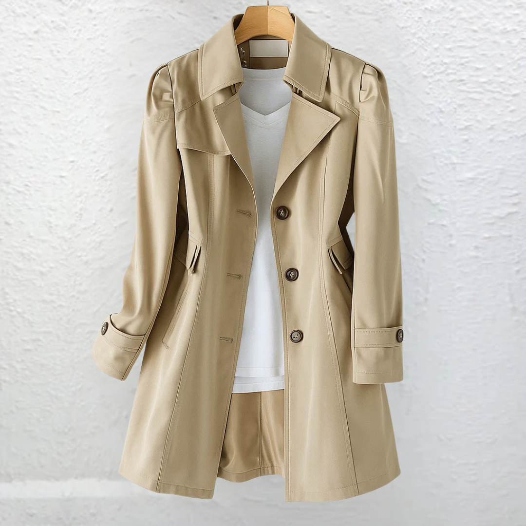 Front view of a beige trench coat with a wide collar, three-button closure, slanted welt pockets, shaped waist, and cuff tabs.