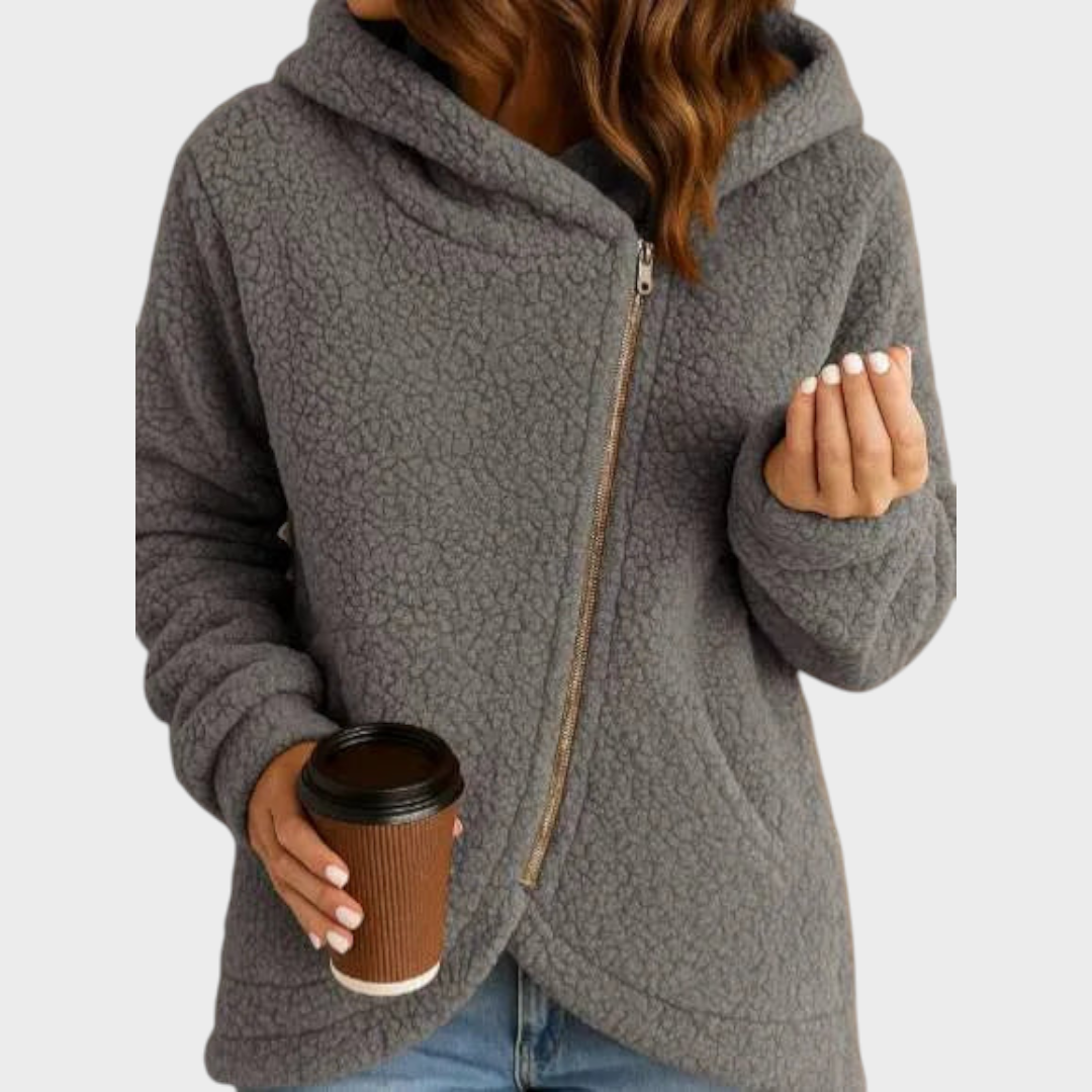Gray teddy textured hooded jacket with a curved hem, long sleeves, and diagonal front zip closure, styled with jeans.