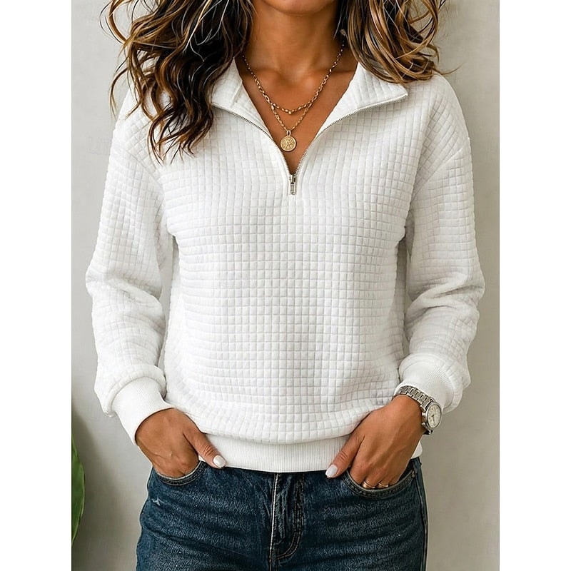 White textured quarter-zip pullover shown from the front with the neckline partially open and both hands in jeans pockets.