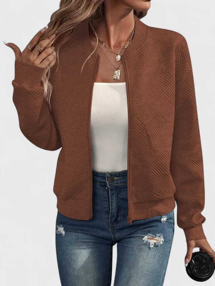 Brown textured bomber jacket showing its geometric pattern, front zipper, gathered cuffs, and waist-length silhouette.