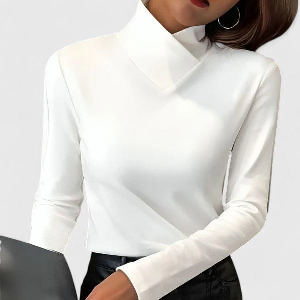 White long-sleeve turtleneck top showing the folded neckline styled with dark trousers.