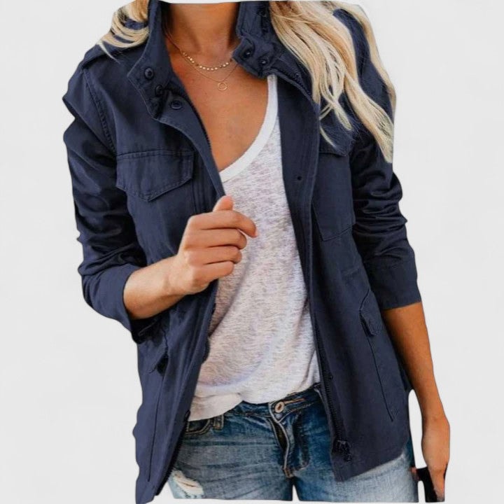 Navy utility jacket styled open over a white top, showing the high snap collar, flap chest pockets, and relaxed long sleeves.