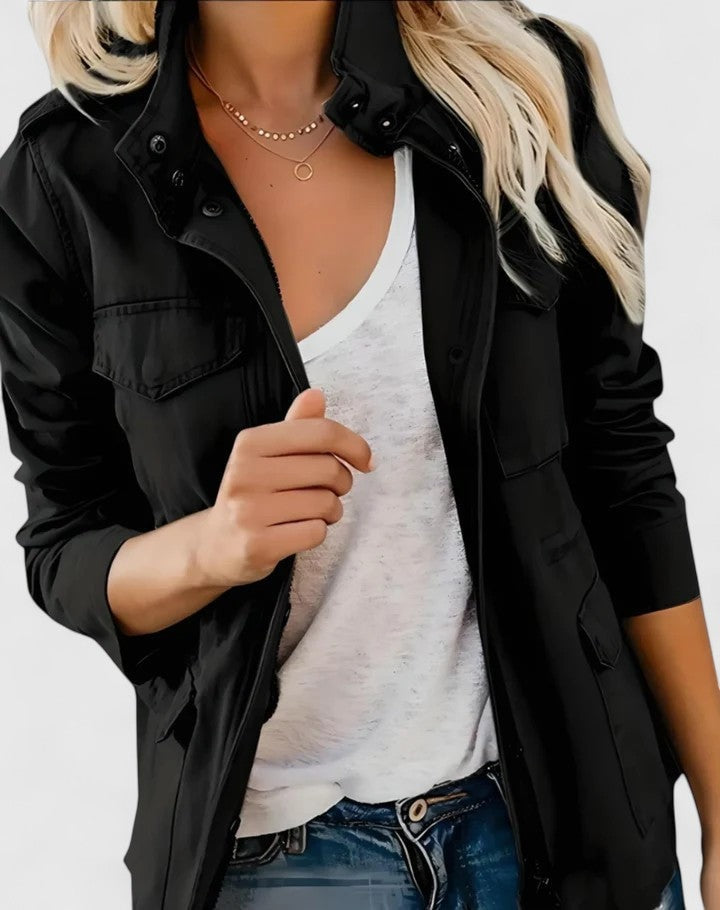 Black utility jacket styled open over a white top, with a structured high snap collar, flap chest pockets, and long sleeves.