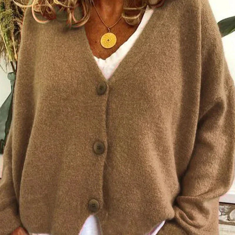 Brown V-neck button-front cardigan worn over a white top, shown with long sleeves and three visible buttons.