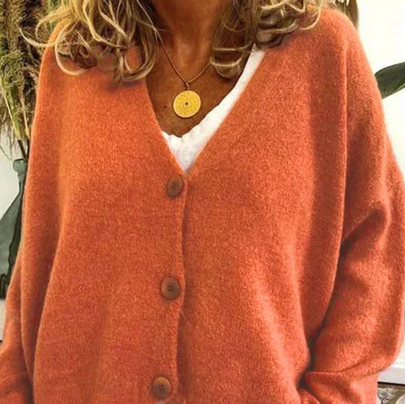 Orange V-neck cardigan shown from the front with dark buttons and softly gathered long sleeves.