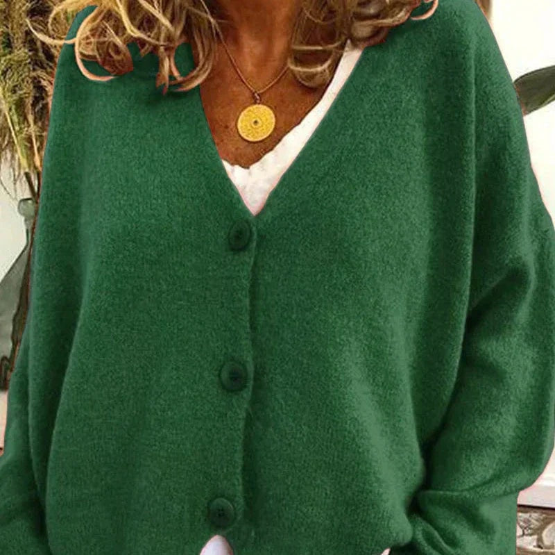 Forest green button-front cardigan worn over a white top, highlighting the V-neckline and long sleeves.