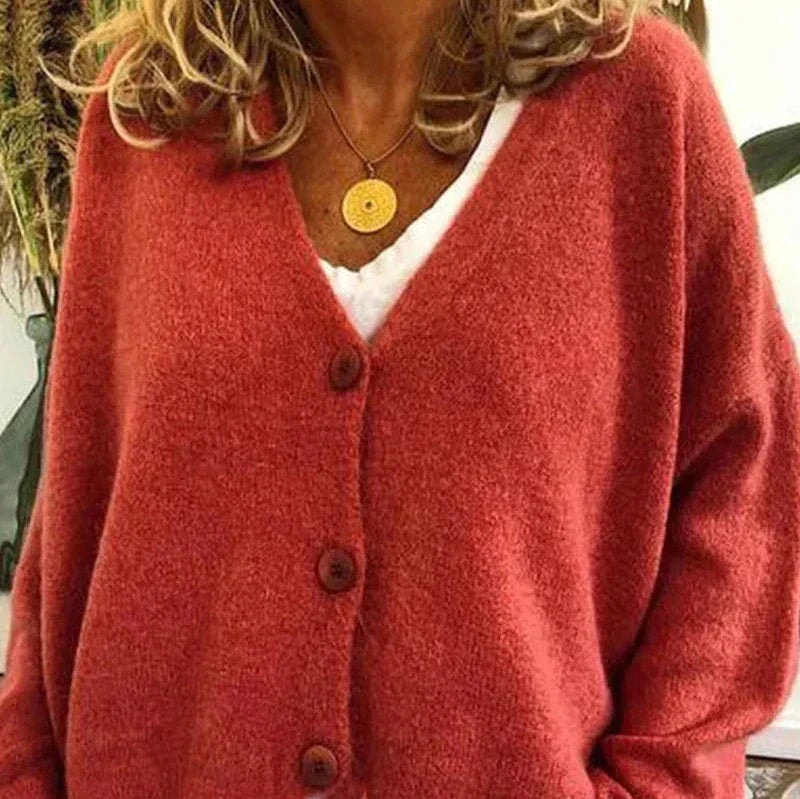 Red cardigan featuring a V-neckline, dark button-front closure, and long sleeves.