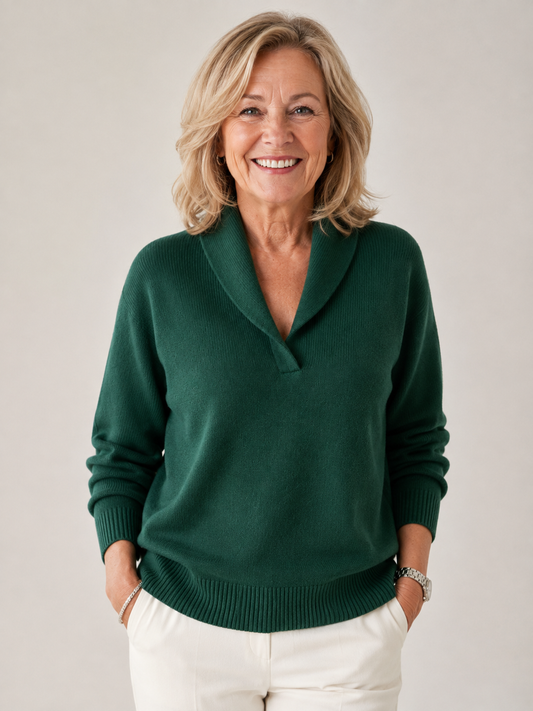 Dark green V-neck sweater with a shawl collar, long sleeves, and ribbed cuffs and hem, shown from the front with cream trousers.