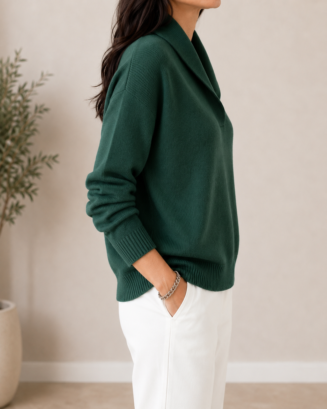 Side view of the dark green V-neck sweater showing the relaxed fit, long sleeve, shawl collar, and ribbed lower edge.